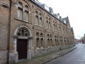 a large brick building with a door on a street at Albertushof in Ieper