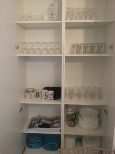 a white pantry with glasses and dishes on shelves at La Pierre Précieuse in Château-Thierry