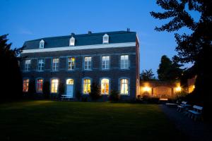 um grande edifício de tijolos com as suas luzes acesas em B&B Het Agnetenklooster em Maaseik