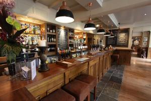 a bar with a long wooden counter in a restaurant at The Bear's Paw in Warmingham