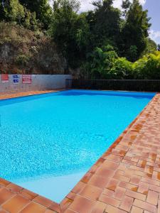 a large blue swimming pool with a brick walkway at Joli T2 à 5 min de la plage in Le Gosier