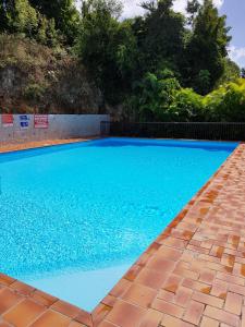 une grande piscine bleue avec une passerelle en briques dans l'établissement Joli T2 à 5 min de la plage, au Gosier