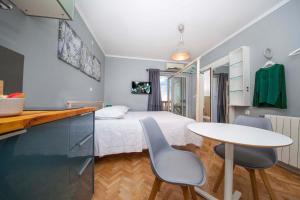 1 dormitorio con 1 cama, mesa y sillas en Villa Makarana Apartments, en Makarska