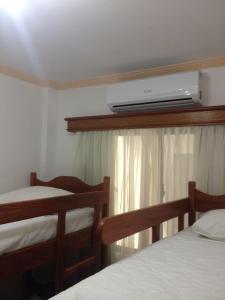 1 dormitorio con 2 camas y TV en la pared en Raio do Sol Residence, en Bombinhas