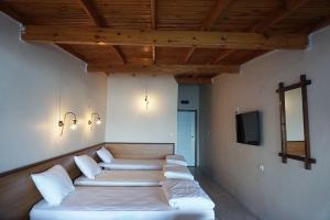 Habitación con una fila de almohadas blancas y TV. en Aqua Boss Hotel, en Eceabat