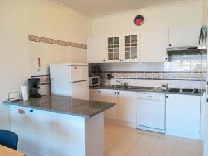eine Küche mit weißen Schränken und einem weißen Kühlschrank in der Unterkunft Apartamento Varandas do Sol Nascente in Porches
