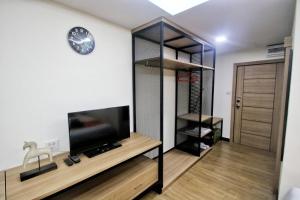 um quarto com uma televisão e uma parede com um relógio em Modern Studio in Nimman - Walking Distance to Mall em Chiang Mai