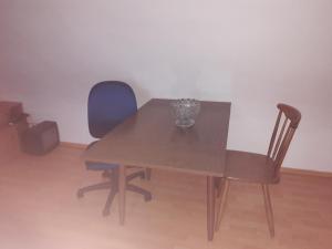 a wooden table with two chairs and a vase on it at Messe Zimmer Düsseldorf Airport in Düsseldorf