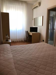 
a hotel room with a bed and a television at Hotel La Sirenetta in Giardini Naxos
