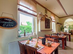a restaurant with a large wooden table and chairs at Kartoffelgasthaus & Pension Knidle in Lübbenau