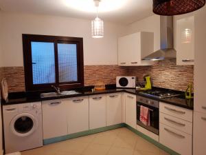 a kitchen with white cabinets and a sink and a window at Appartement B-23 Cabo Négro in Cabo Negro