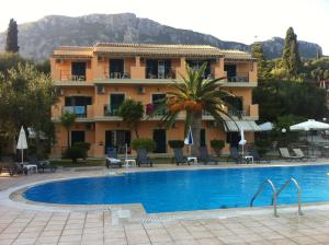a hotel with a swimming pool in front of a building at RoyalRose in Paleokastritsa