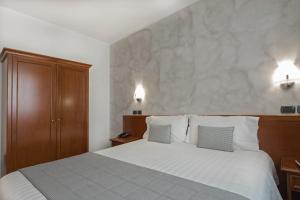 een slaapkamer met een groot wit bed met 2 kussens bij Hotel Medea - Adults Only in Alba