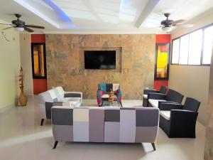 a living room with a couch and chairs and a tv at Hotel Apart Guayaquil Aeropuerto in Guayaquil