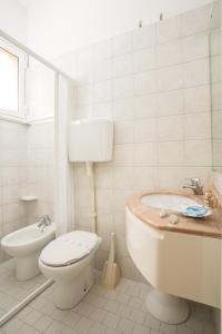 a white bathroom with a toilet and a sink at Hotel Oregon in Rimini