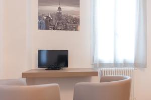 ein Wohnzimmer mit einem TV und 2 Stühlen in der Unterkunft Corte Maggiore in Ravenna