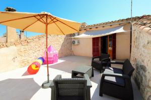 un patio con sombrilla, sillas y mesa en Casa Es Forn 229 by Mallorca Charme en Petra