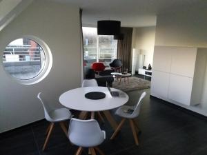 een woonkamer met een witte tafel en stoelen bij Vakantie Appartement Ella in De Haan