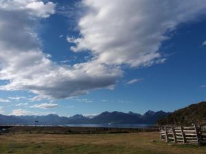 a fence in a field next to a body of water at Hotel Fio Fio in Puerto Williams