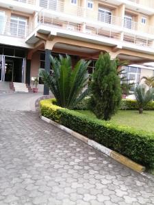 un edificio con palmeras frente a una calle en Western Meridian Hotel Ltd Bushenyi, en Bushenyi