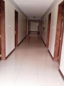einen leeren Flur in einem Gebäude mit weißen Böden und Türen in der Unterkunft Western Meridian Hotel Ltd Bushenyi in Bushenyi