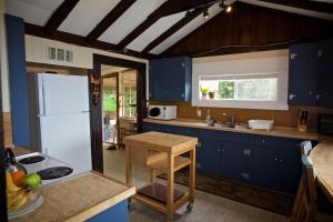 a kitchen with blue cabinets and a white refrigerator at Halfmoon Haven Beach Cottage or Oceanview Suite in Halfmoon Bay