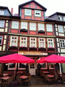 ein Restaurant mit roten Sonnenschirmen vor einem Gebäude in der Unterkunft Ratsstübchen in Wernigerode
