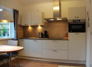 a small kitchen with white cabinets and a table at vakantiewoning 72 in Oostkapelle