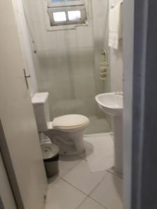 uma casa de banho branca com um WC e um lavatório em Pousada do Pascoal em Juqueí