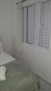 a white bedroom with a bed and two windows at Pousada do Pascoal in Juquei