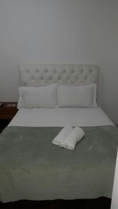 uma grande cama branca com uma cabeceira e almofadas brancas em Pousada do Pascoal em Juqueí