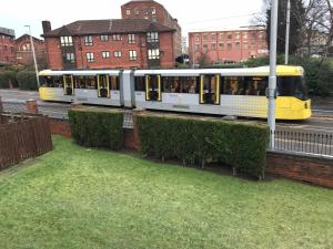 a yellow and white train traveling down a street at Flat 9a Badby Close in Manchester