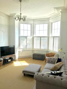 a living room with a couch and a tv at Elegant Spacious Seaside Apartment in St. Leonards