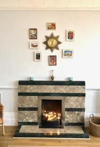 a living room with a stone fireplace with a clock on the wall at Elegant Spacious Seaside Apartment in St. Leonards