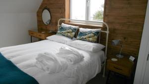 a bed in a bedroom with a white comforter and pillows at Breakish Escape - near Broadford in Breakish