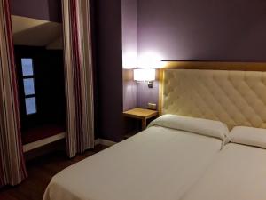 a bedroom with a large white bed and a lamp at Hospedería Santa Elena in San Carlos del Valle