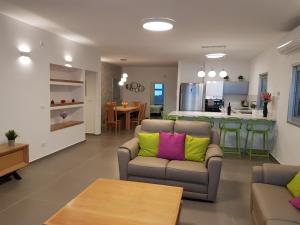 - un salon avec un canapé et des oreillers colorés dans l'établissement Nitza Boutique Apartment Kosher, à Netanya