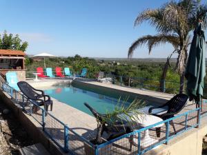 a swimming pool with two chairs and umbrellas at Complejo Sierras in Villa Parque Siquiman