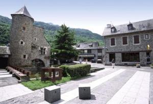 a group of buildings in a courtyard with a tree at Agréable studio cabine à ST LARY SOULAN - 5 couchages in Saint-Lary-Soulan