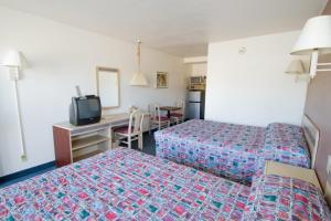 a hotel room with two beds and a desk at Brooks St. Motor Inn in Missoula