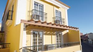 a yellow house with balconies on a street at Encosta das Oliveiras 49D in Vilamoura