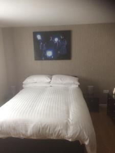 a bedroom with a white bed with a tv on the wall at Liverpool Apartments in Liverpool