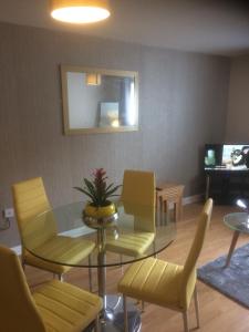 a living room with a glass table and yellow chairs at Liverpool Apartments in Liverpool
