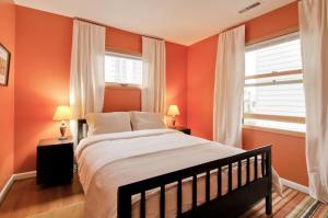 1 dormitorio con paredes de color naranja, 1 cama y 2 ventanas en Doyle Lovejoy, en Portland