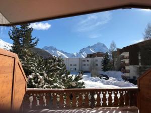 un balcón con un árbol de Navidad y montañas cubiertas de nieve en Résidence le Plein Sud, en Les Deux Alpes