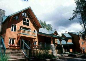 Une grande maison en bois avec des escaliers se trouve juste devant. dans l'établissement HI Lake Louise Alpine Centre - Hostel, à Lake Louise