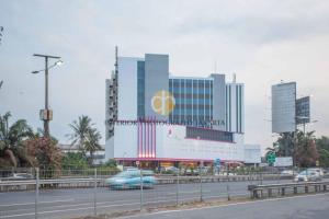 a large building with a sign on it next to a highway at Orchardz Hotel Bandara in Tangerang