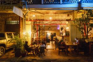 um grupo de pessoas sentadas num restaurante à noite em Pomme Hostel Restaurant & Bar - Private Sleeping Cabins em Battambang