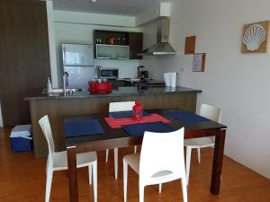 - une cuisine avec une table en bois et des chaises blanches dans l'établissement Apartment Bala Beach, à María Chiquita