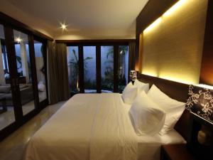 1 dormitorio con 1 cama grande con sábanas y almohadas blancas en Grania Bali Villas, en Seminyak